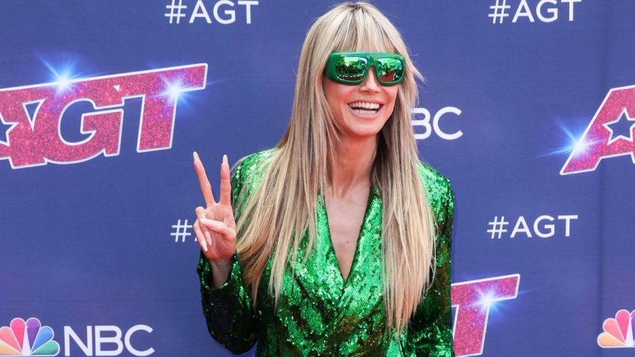 Heidi Klum mit grüner Glitzerjacke und Sonnenbrille macht das Peace-Zeichen