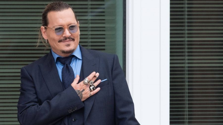 Johnny Depp legt sich die Hand aufs Herz und lächelt