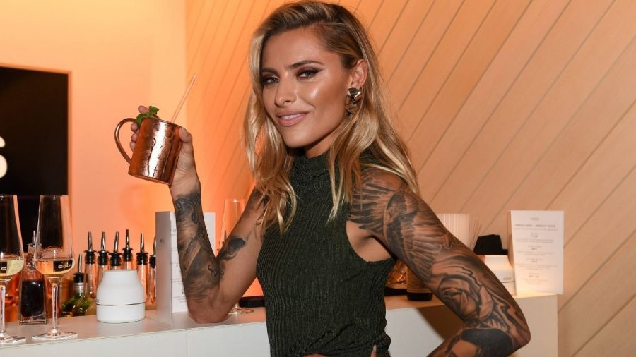 Sophia Thomalla hebt einen Drink und lächelt