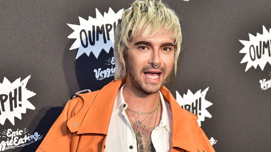 Bill Kaulitz setzt zum Reden an in einem orangenem Mantel