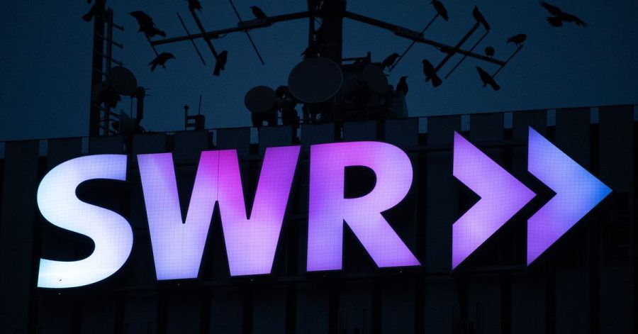 Das Logo des Südwestrundfunks (SWR) leuchtet am frühen Morgen am Funkhaus in Stuttgart. (Archivbild)